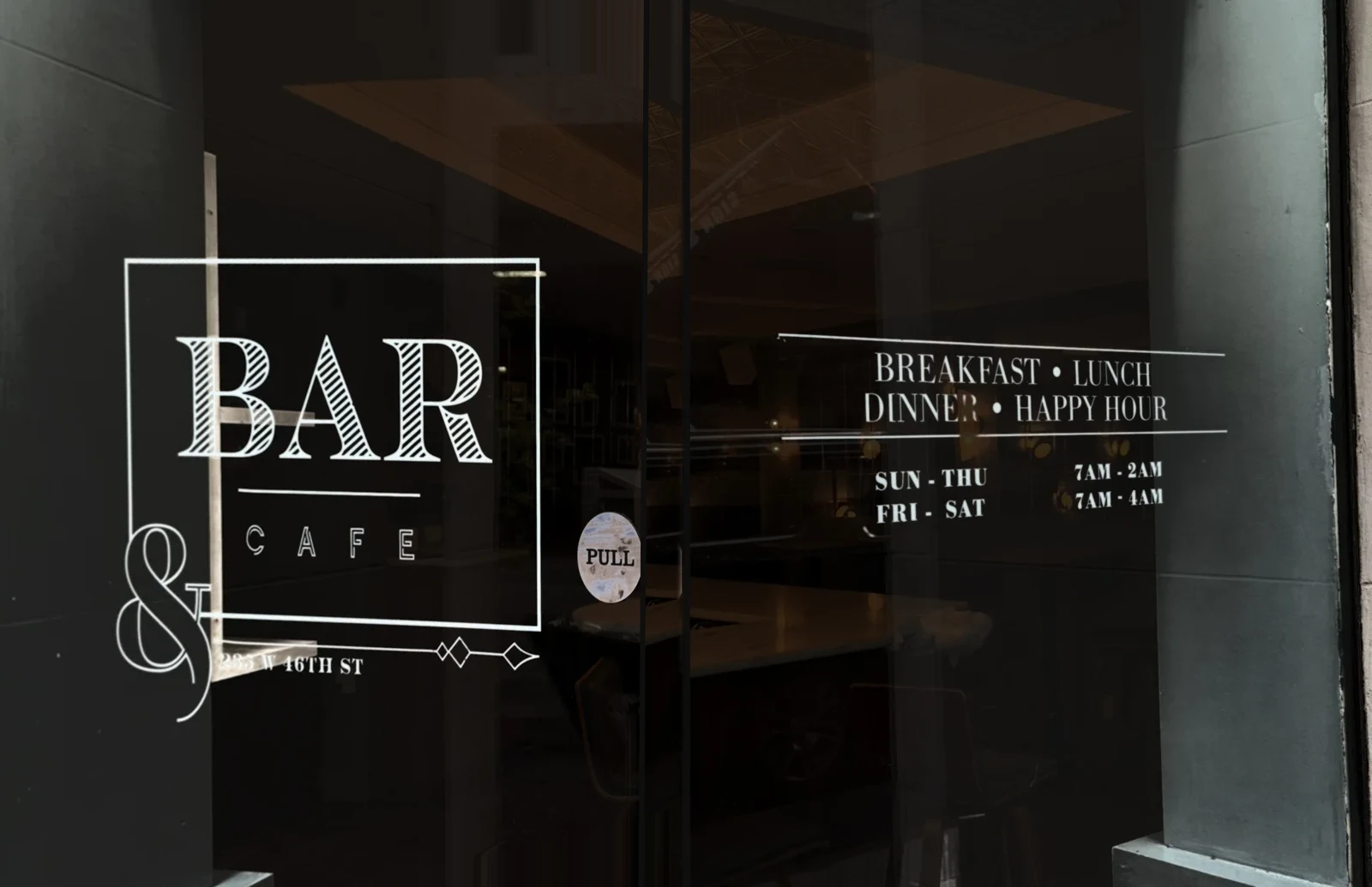 Eye-level view of the two glass doors: the Bar and Café mark and the hours engraving, with the room behind darkened