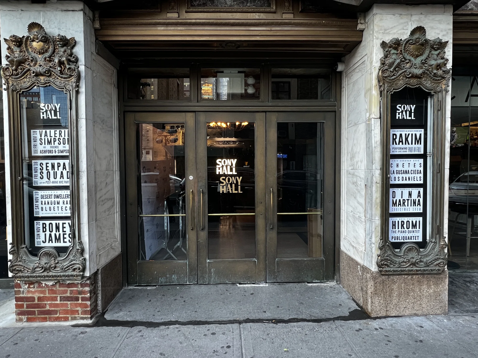 Sony Hall entrance on West 46th Street: marble pilasters with the bronze marquee cases either side of the doors, billing Rakim, Chetes, Dina Martina and Hiromi