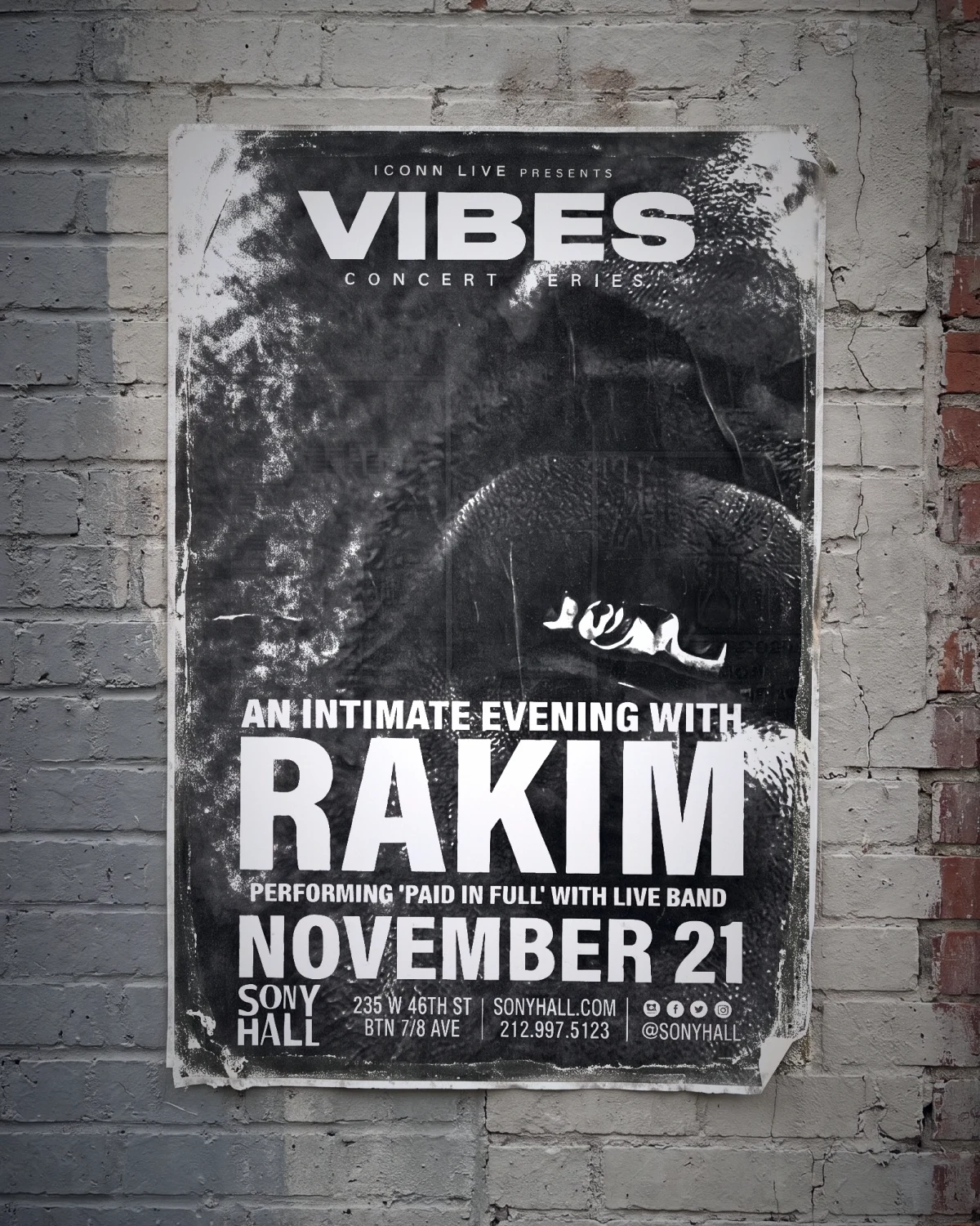Rakim print pasted on a painted brick wall, shot with flash