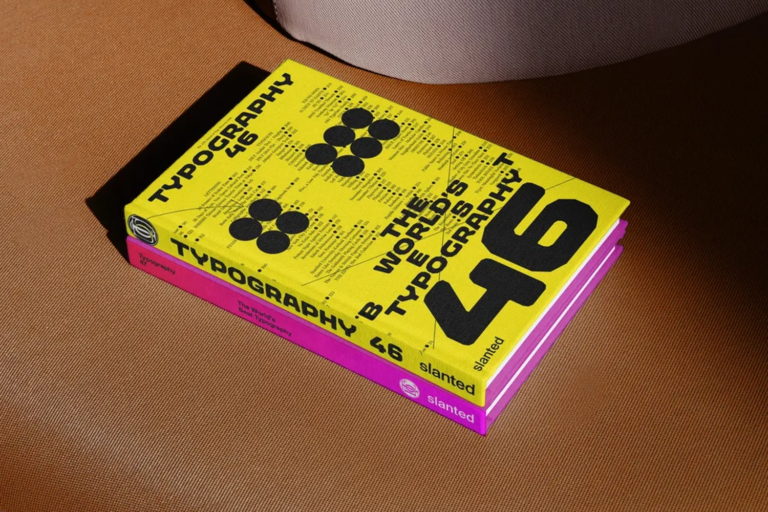 Typography 46 in yellow stacked on Typography 47 in pink, on a leather bench